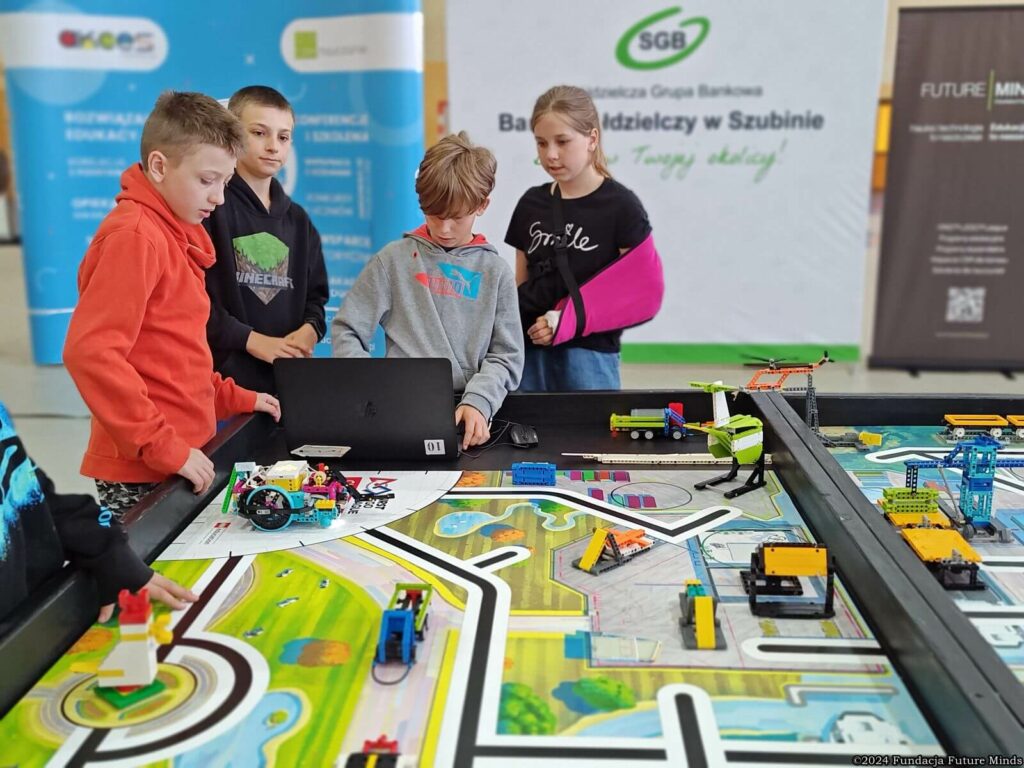 Dzieci uczą się programowania robotów na interaktywnej planszy z atrakcyjnymi elementami edukacyjnymi.